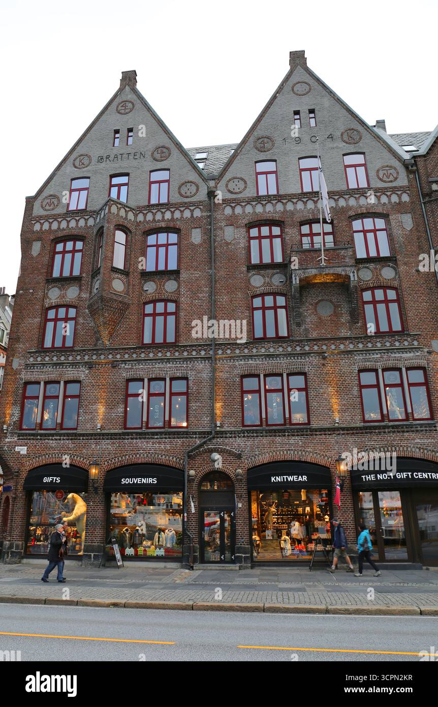 Bergen, Norvegia - 15 settembre 2025: Persone non identificate camminano accanto all'edificio storico con negozio di souvenir accanto al porto Foto Stock