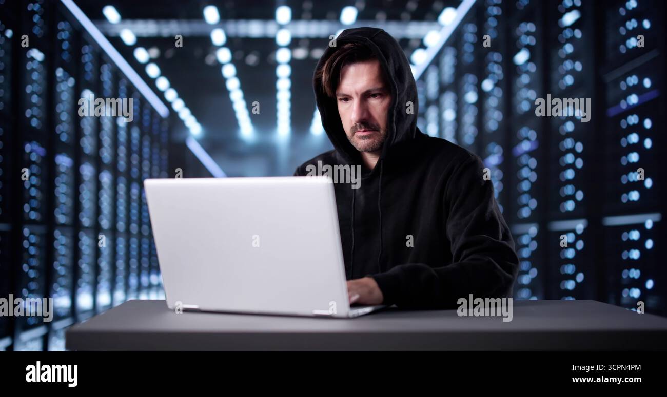 Hacking di uomo sospetto in maschera nel server online per scopi dannosi. Foto Stock