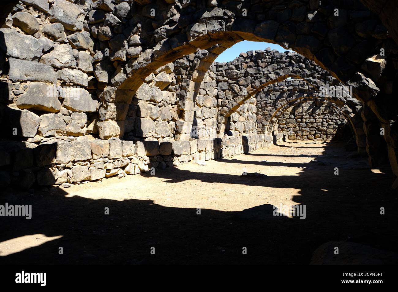 L'antico castello di Azraq (Qasr al-Azraq) sotto il sole splendente nell'arido paesaggio desertico giordano Foto Stock