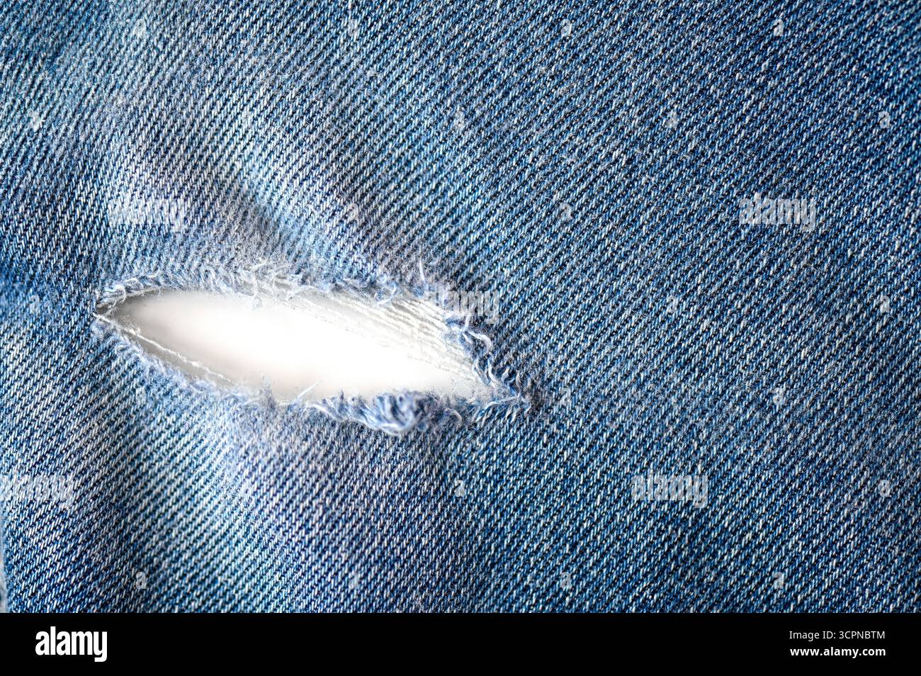 Vista dall'alto dei jeans danneggiati e lacerati con un foro come trama o sfondo, spazio per il testo Foto Stock