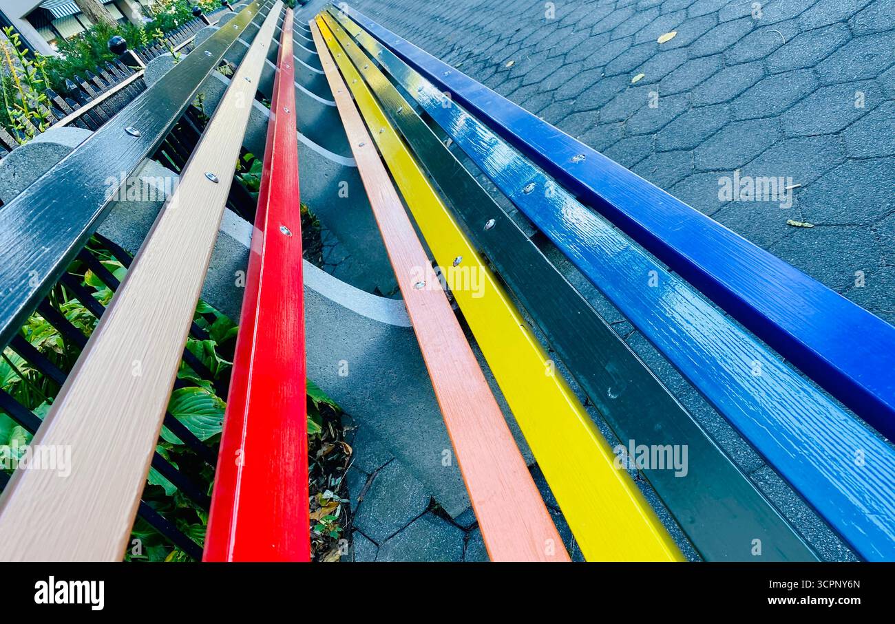 Panchine colorate in legno in Gradient Row lungo un sentiero pavimentato - Immagine stock catturata con smartphone