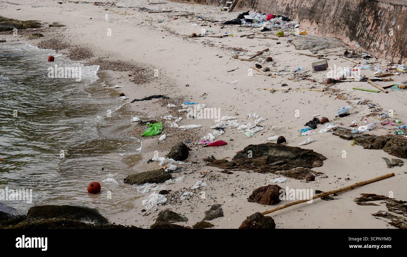 Inquinamento ambientale con bottiglie di plastica e rifiuti sparsi sulla spiaggia sabbiosa vicino al mare. Foto Stock