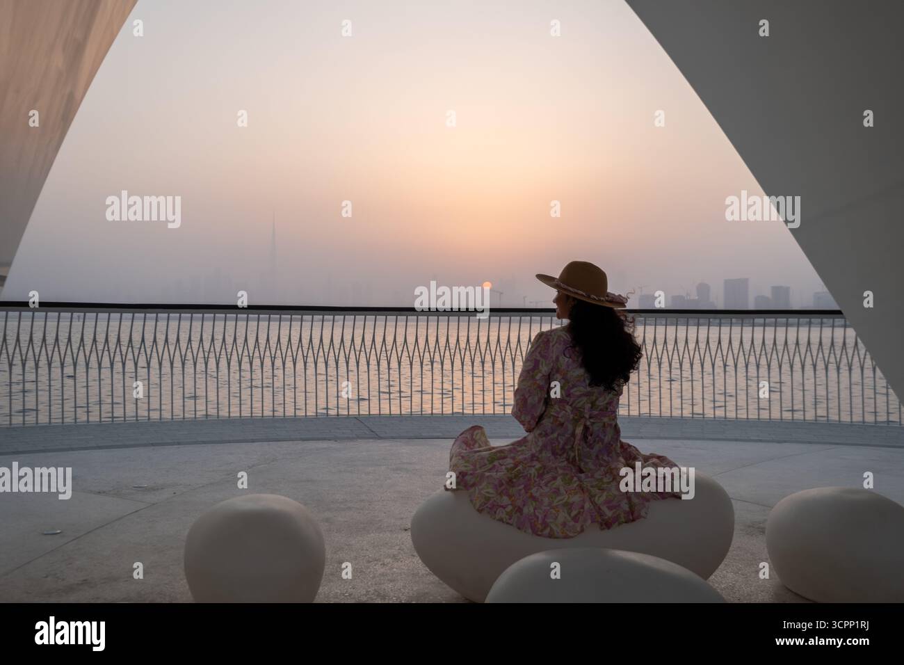 Donna seduta sotto una moderna tettoia al tramonto del porto di dubai creek, viaggi di lusso e stock di stile di vita in 4K pro res Foto Stock