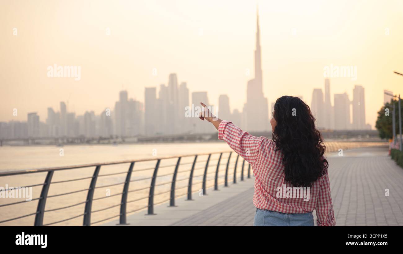 Sfondo immobiliare a Dubai con donna che punta verso lo skyline, con spazio per le copie, carta da parati poster 4k Foto Stock