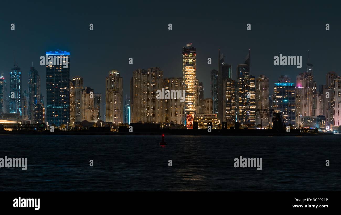Vista notturna dello skyline di Dubai Marina con moderni grattacieli, Dubai Ain e crociera a vela sui riflessi del mare Foto Stock