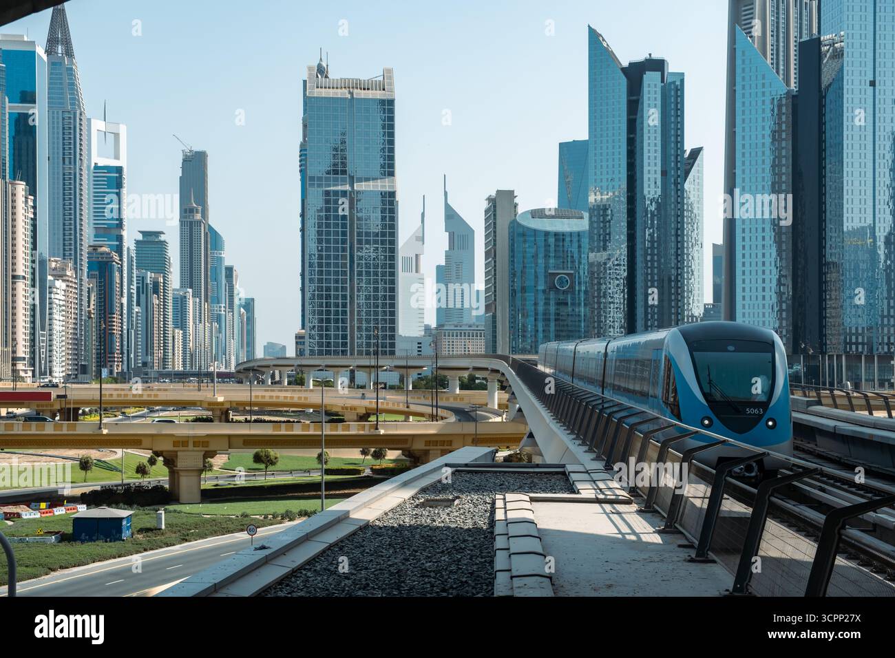 Vista dello skyline del centro di Dubai con il treno della metropolitana che corre lungo i binari ferroviari sopraelevati, circondato da torri di vetro e moderni grattacieli per uffici Foto Stock