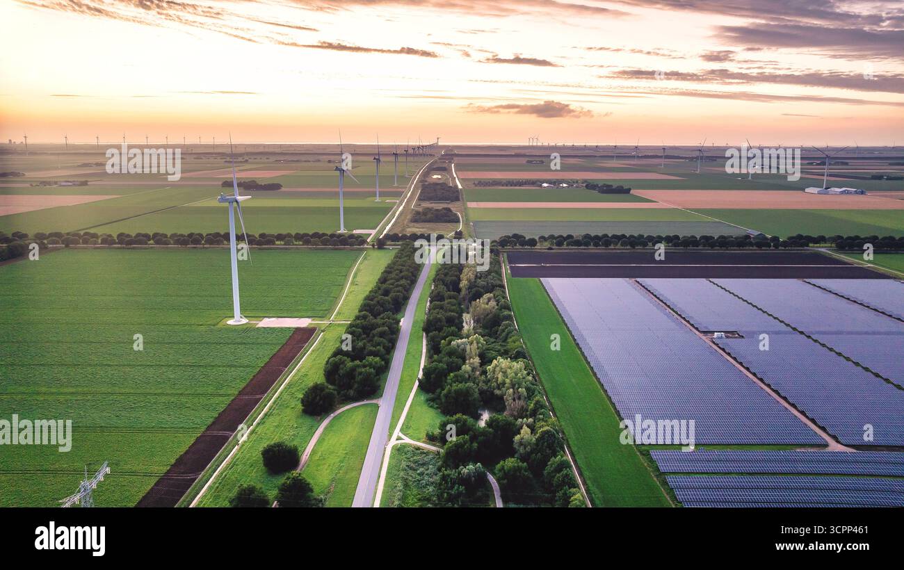 Vista dal drone del paesaggio rurale serale con centrali eoliche e solari nei Paesi Bassi. Mulini a vento lungo i campi agricoli dopo il tramonto. Alternativa en Foto Stock