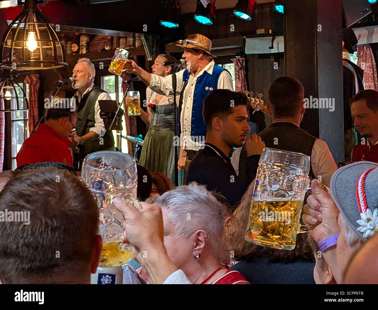 Monaco, Germania. 26 settembre 2025. I visitatori allevano tazze da birra all'interno di una tenda durante l'Oktoberfest a Monaco, Baviera, Germania, il 26 settembre 2025. Una band si esibisce sul palco mentre la gente festeggia con i tradizionali filetti di birra. (Foto di Michael Nguyen/NurPhoto) credito: NurPhoto SRL/Alamy Live News Foto Stock