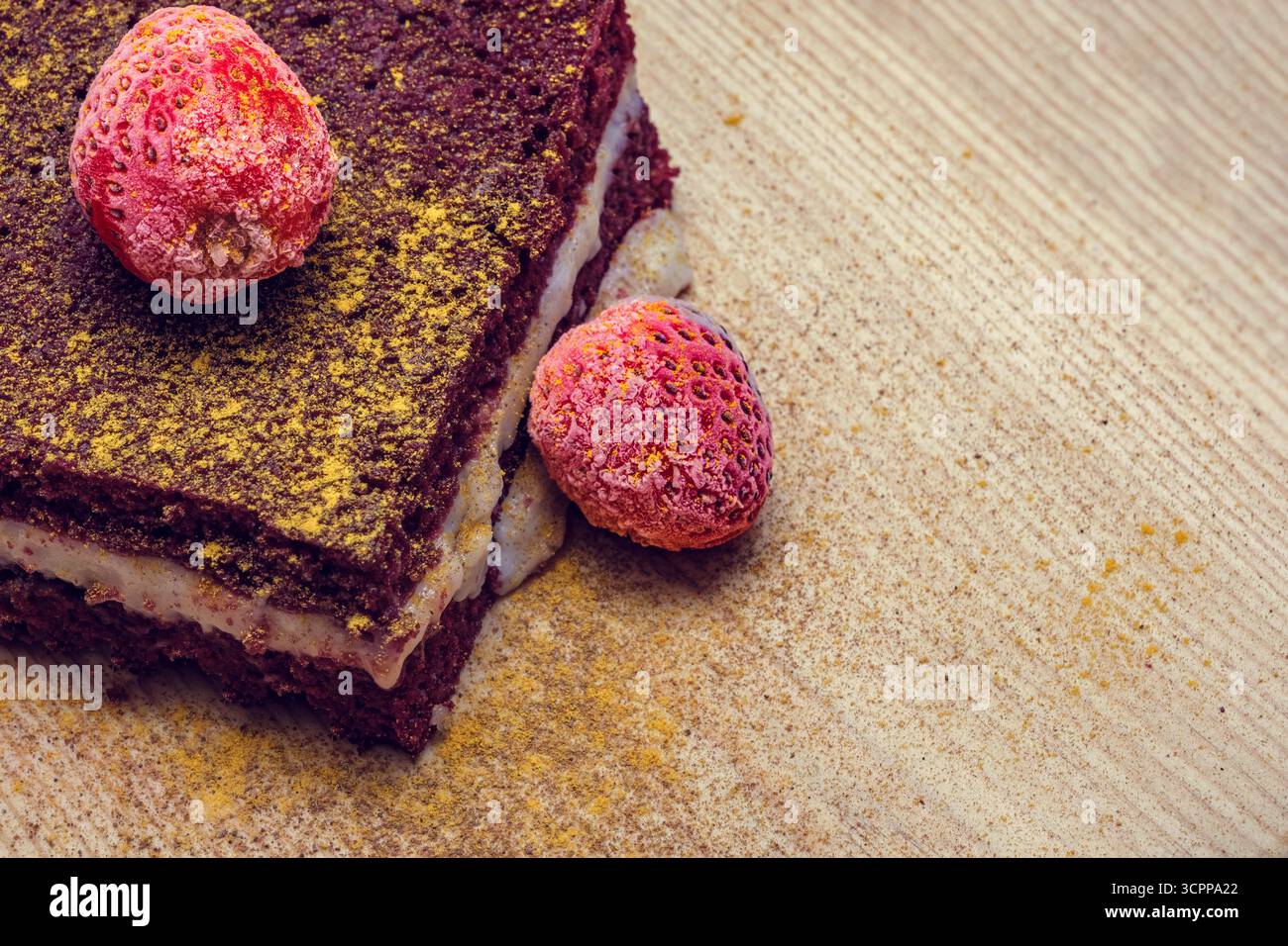 Una vista ravvicinata di una fetta di torta di velluto rosso con strati cremosi e fragole fresche, cosparse di condimenti vivaci, su una texture Foto Stock