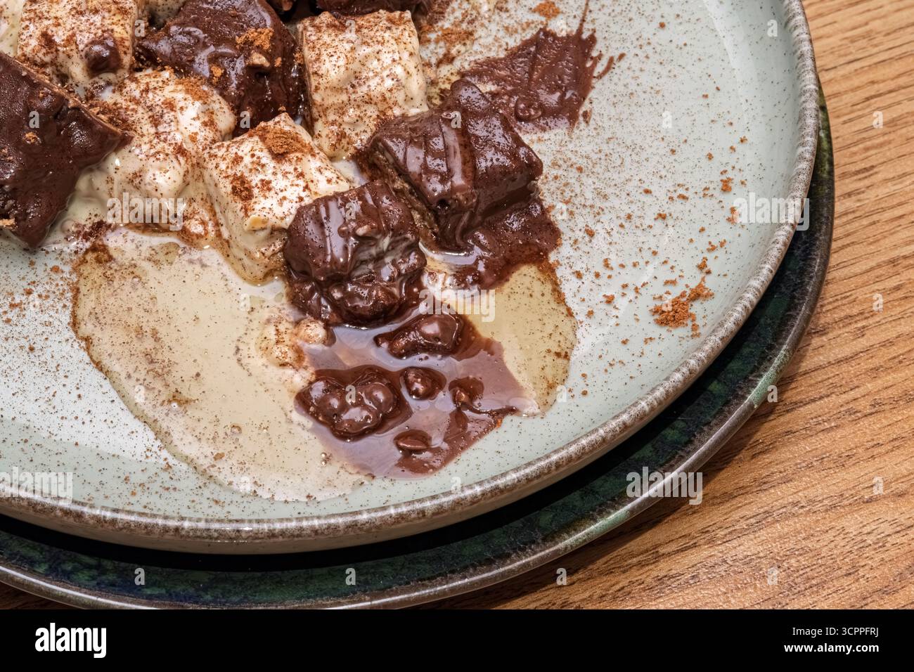 Cioccolato e dessert cremoso con spolveratura di cacao. Il piatto è guarnito con una spolverata di cacao in polvere, creando un contrasto di consistenze e sapori. Foto Stock