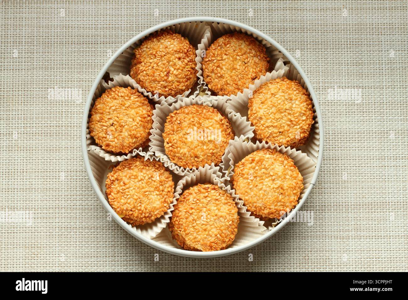 Biscotti al sesamo avvolti in involucri di carta e collocati in una scatola di metallo. Vista dall'alto. Primo piano Foto Stock