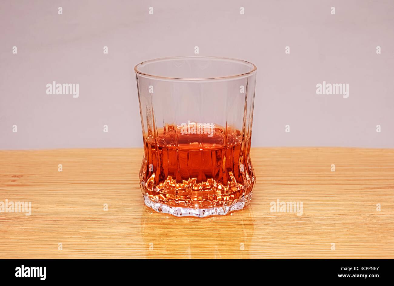 Bicchiere per bevande su un tavolo in legno con sfondo neutro. Il bicchiere con una bevanda è centrato su un tavolo di legno chiaro. Adatto per bevande e stili di vita Foto Stock