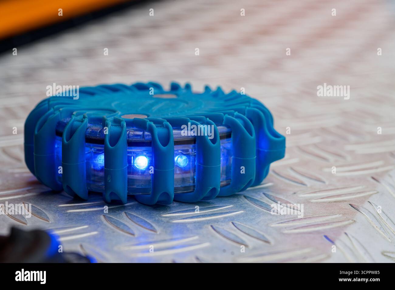 Primo piano di una spia di emergenza a LED blu sulla superficie metallica. Perfetto per la sicurezza, il salvataggio, i concetti di pericolo, la prevenzione degli incidenti o la sicurezza a tema V Foto Stock