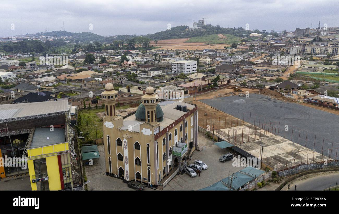 Vista aerea di una moschea con le sue pareti beige chiare che contrastano con le sue cupole verdi, che si erge come un faro di fede nel mezzo della proliferazione urbana, Old BOD Foto Stock