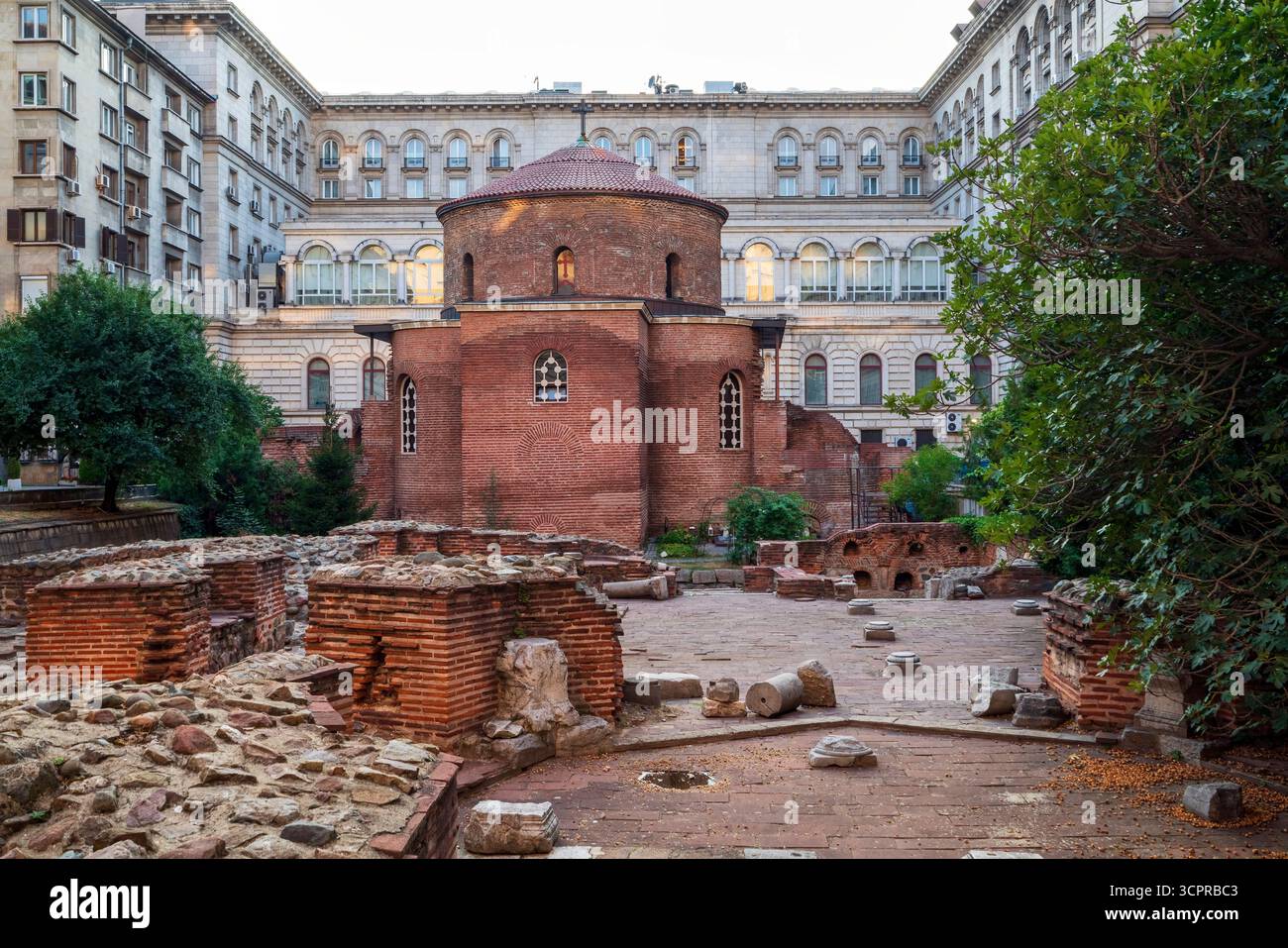L'antica Rotonda di San Giorgio a Sofia, Bulgaria, una chiesa paleocristiana in mattoni rossi circondata da rovine romane ed edifici moderni. Foto Stock