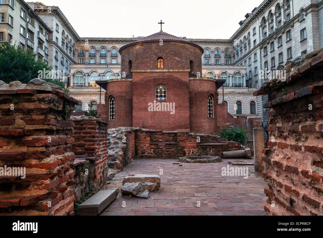L'antica Rotonda di San Giorgio a Sofia, Bulgaria, una chiesa paleocristiana in mattoni rossi circondata da rovine romane ed edifici moderni. Foto Stock