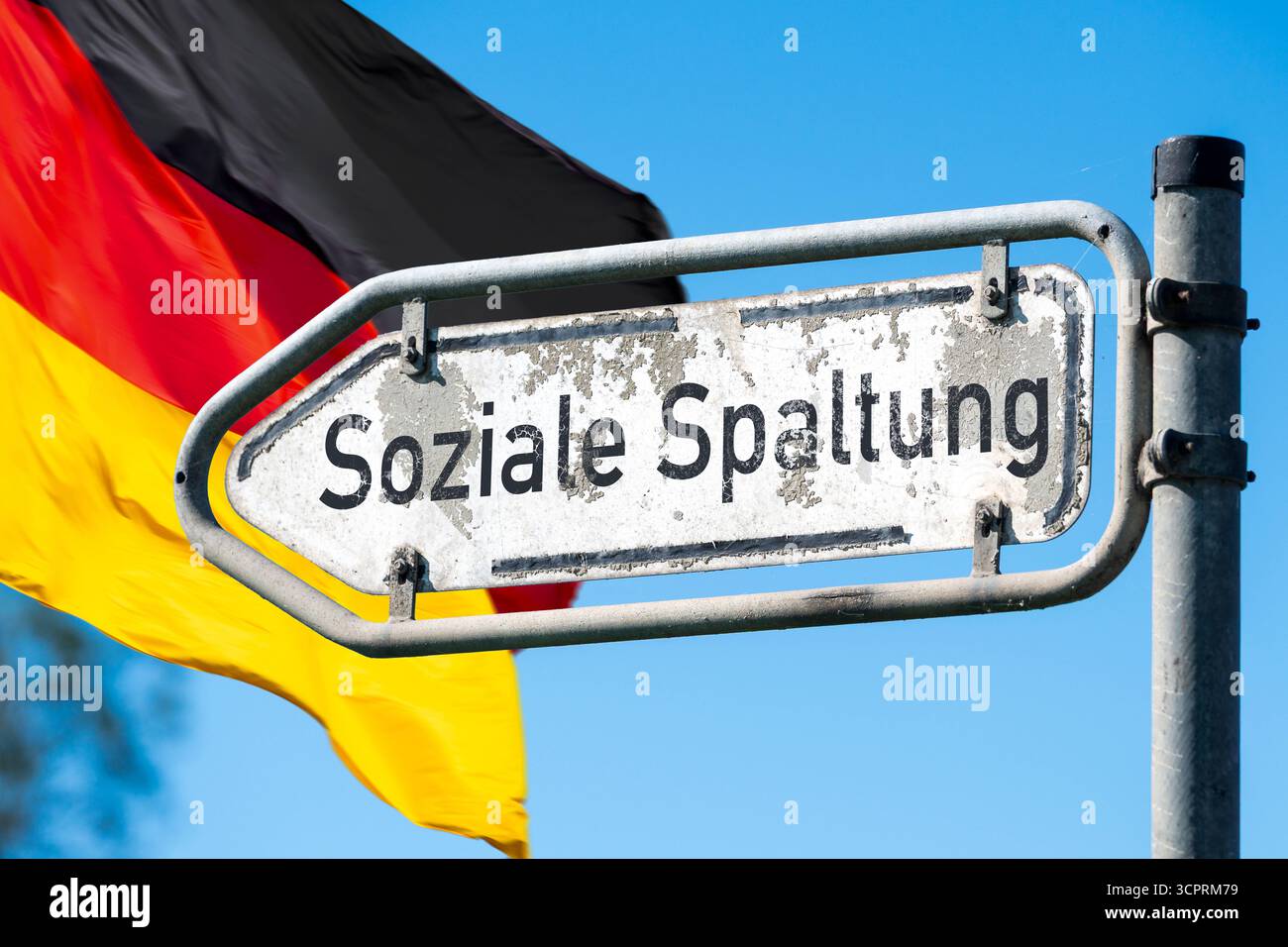 Germania - 27 settembre 2025: FOTOMONTAGGIO, Un segno intempestivo che legge Social divide di fronte alla bandiera tedesca evidenzia le divisioni sociali. Politica, economia e migrazione stanno esacerbando disuguaglianze, polarizzazione e crescenti conflitti. *** FOTOMONTAGE, Ein verwittertes Schild Soziale Spaltung vor deutscher Flagge macht gesellschaftliche Brüche sichtbar. Politik, Wirtschaft und Migration verstärken Ungleichheit, Polarisierung und wachsende Konflikte. Foto Stock
