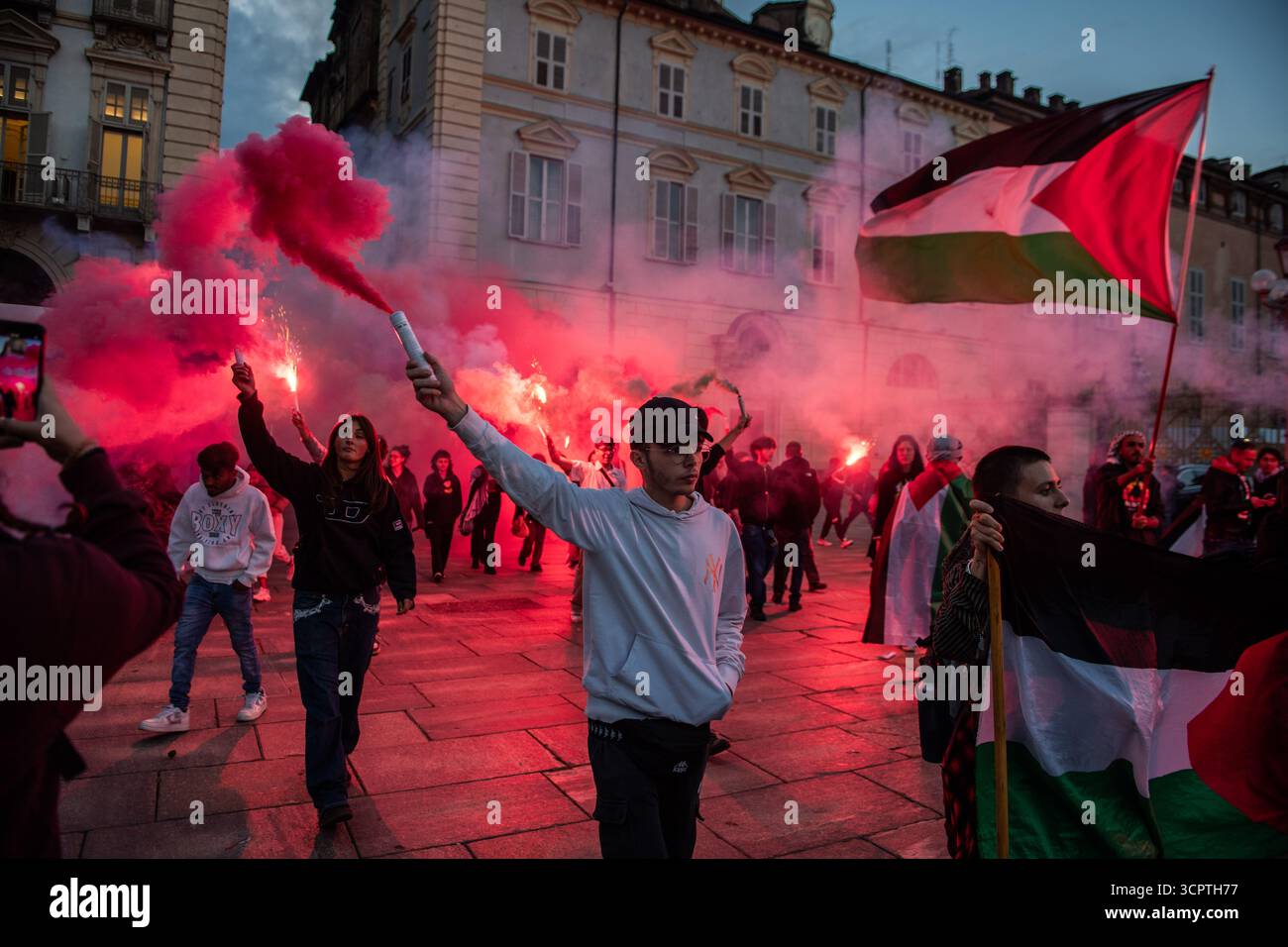 Torino, Abruzzo, Italia. 27 settembre 2025. i manifestanti cercano di arrivare all'aeroporto per bloccarlo. Fermati dalla polizia, decidono di bloccare il centro città. La protesta è arrivata poi al "salone auto Torino", l'esposizione annuale di automobili di Torino. Un tizio sta tenendo in mano una bomba fumogena e altri stanno tenendo le torce. Bandiera Palestina sullo sfondo (immagine di credito: © Sebastiano Bacci/ZUMA Press Wire) SOLO PER USO EDITORIALE! Non per USO commerciale! Foto Stock