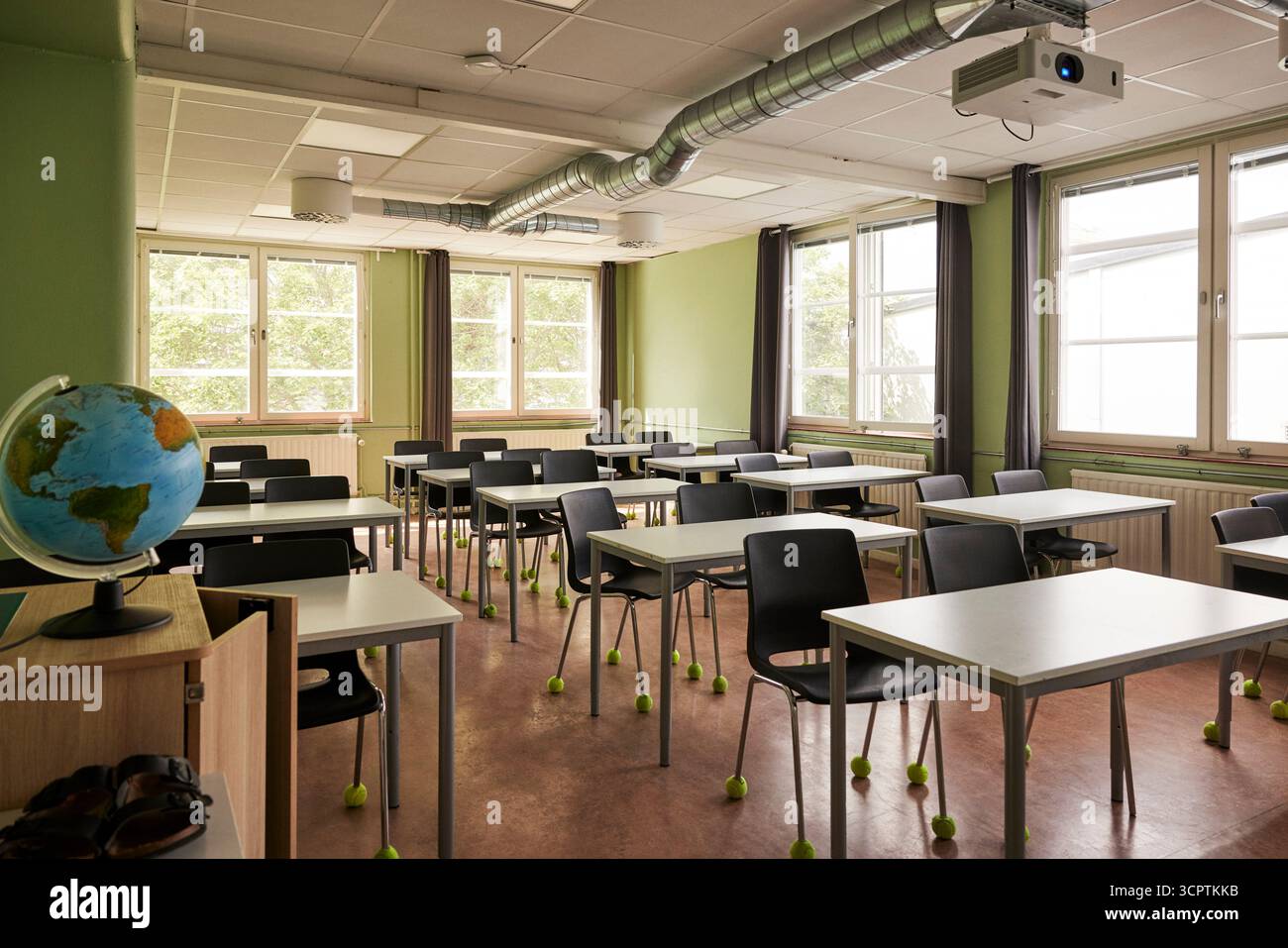 Aula vuota con globo vicino a scrivanie e sedie nell'edificio delle scuole medie Foto Stock