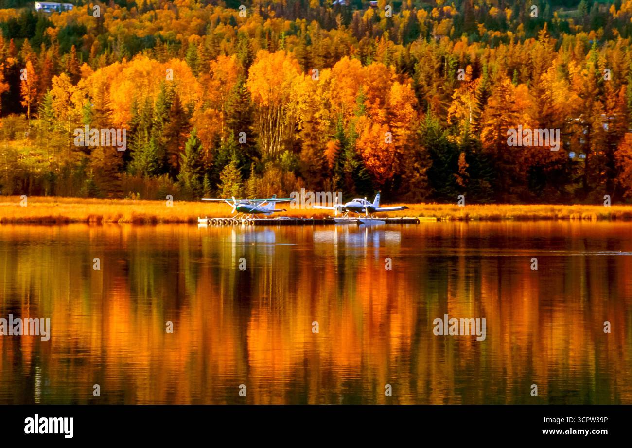 Due idrovolanti sono ormeggiati su un lago circondato da una foresta dai colori autunnali che si riflettono nell'acqua. Foto Stock