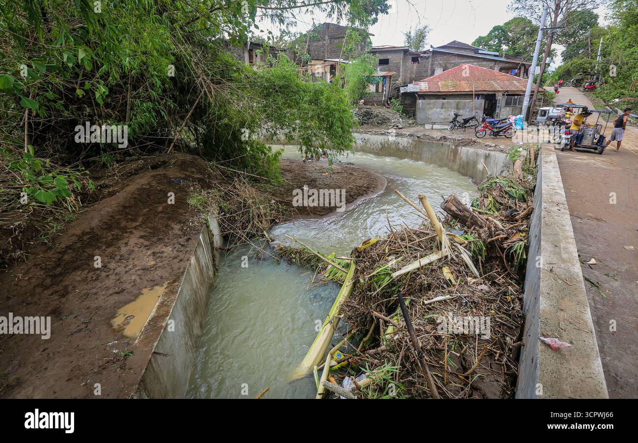 Calabarzon, Filippine. 28 settembre 2025. Meno di 48 ore dopo l'ultima tempesta, i detriti delle inondazioni rimangono bloccati contro i tombini del ponte. Il livello del fiume è già sceso, rivelando tronchi di alberi e rami trasportati dalle acque gonfie, formando un blocco sotto la strada. L'arcipelago delle Filippine è stato colpito da due sistemi tropicali in quattro giorni. Il Super tifone Ragasa (Nando) colpì Luzon settentrionale il 22 settembre con venti distruttivi e forti piogge. Giorni dopo, una grave tempesta tropicale Bualoi (Opong) colpì le regioni centrali il 26 settembre, causando inondazioni ed evacuazioni. Crediti: Kevin Izorce/Alamy Live News Foto Stock Calabarzon, Filippine. 28 settembre 2025. Meno di 48 ore dopo l'ultima tempesta, i detriti delle inondazioni rimangono bloccati contro i tombini del ponte. Il livello del fiume è già sceso, rivelando tronchi di alberi e rami trasportati dalle acque gonfie, formando un blocco sotto la strada. L'arcipelago delle Filippine è stato colpito da due sistemi tropicali in quattro giorni. Il Super tifone Ragasa (Nando) colpì Luzon settentrionale il 22 settembre con venti distruttivi e forti piogge. Giorni dopo, una grave tempesta tropicale Bualoi (Opong) colpì le regioni centrali il 26 settembre, causando inondazioni ed evacuazioni. Crediti: Kevin Izorce/Alamy Live News Foto Stock