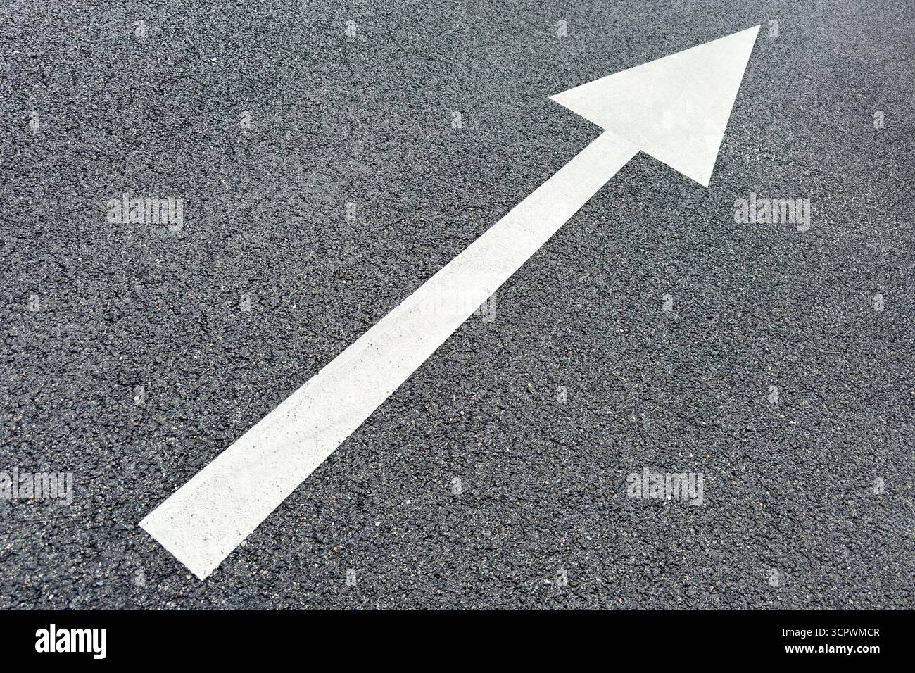 Freccia direzionale bianca dipinta su asfalto scuro, che indica il movimento in avanti o la guida, spesso vista su strade, parcheggi o sentieri. Foto Stock