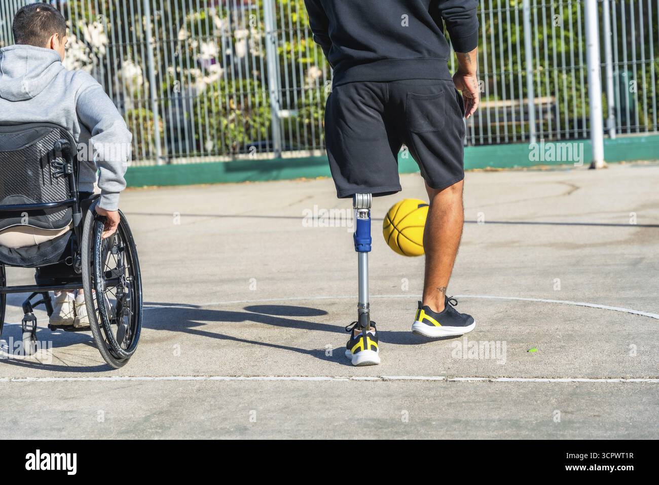 Giovani con disabilità che giocano una partita di basket insieme su un campo all'aperto, abbracciando sport, amicizia e inclusione mentre dimostrano AC Foto Stock