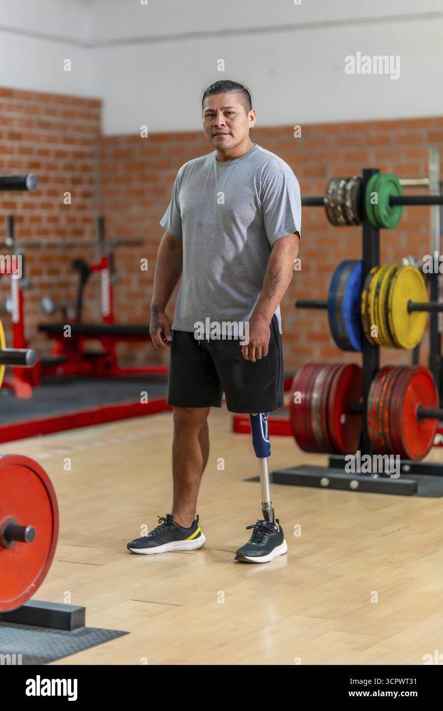 Atleta amputato maschio in piedi in una palestra con sicurezza, mostrando la sua gamba protesica e simboleggiando la resilienza, il fitness e il superamento delle sfide in A. Foto Stock