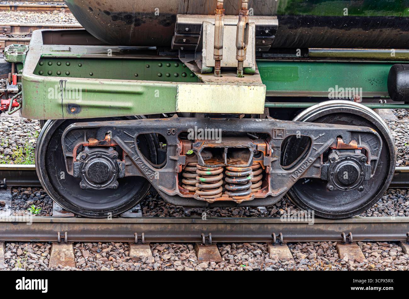 Vista ravvicinata di un treno merci con ruote e sistema di sospensione del carrello sui binari ferroviari Foto Stock