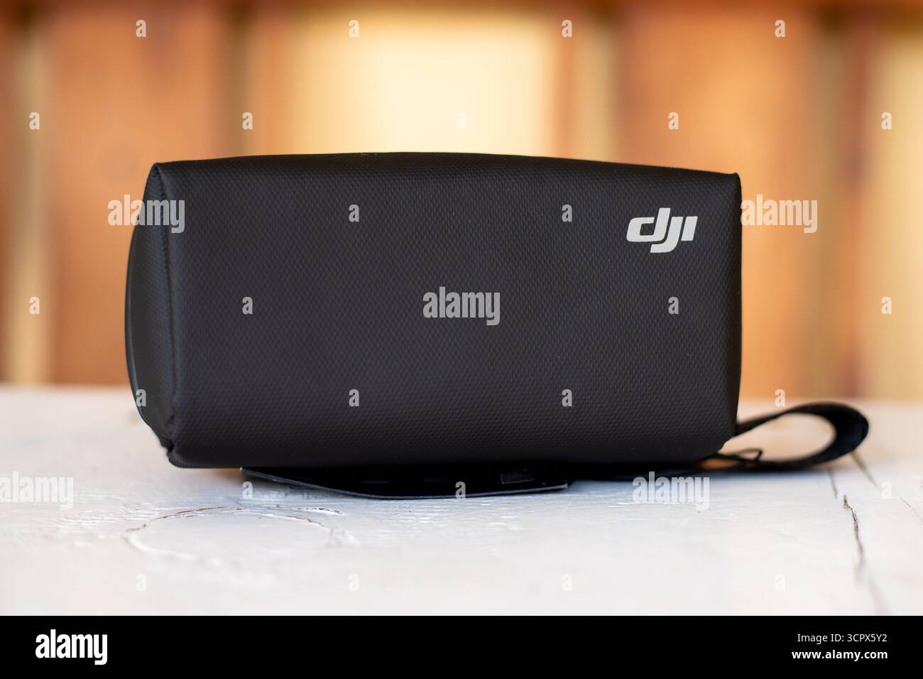 Custodia protettiva da trasporto con marchio DJI con tracolla su tavolo in legno con sfondo sfocato Foto Stock