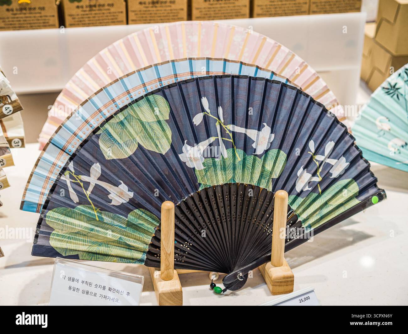 Seoul, Corea del Sud - 23 settembre 2025: Ventilatore pieghevole in tessuto con design Lotus e Orchidea presso il National Museum of Korea Gift Shop Foto Stock