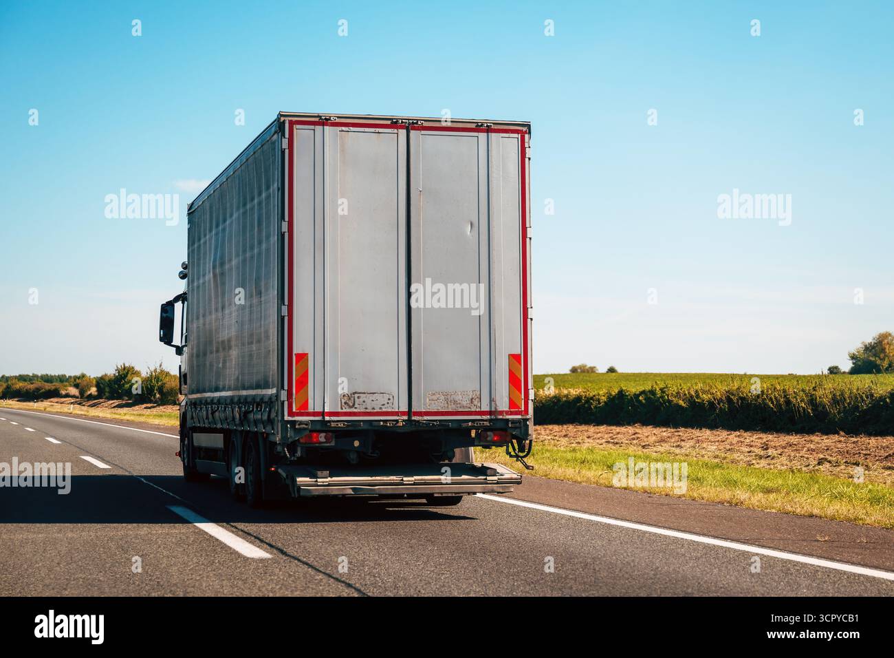 Vista posteriore di un semi-camion con rimorchio con cassone per furgoni a secco che viaggia su autostrada, utilizzato per il trasporto di merci e merci di valore elevato. Messa a fuoco selettiva. Foto Stock