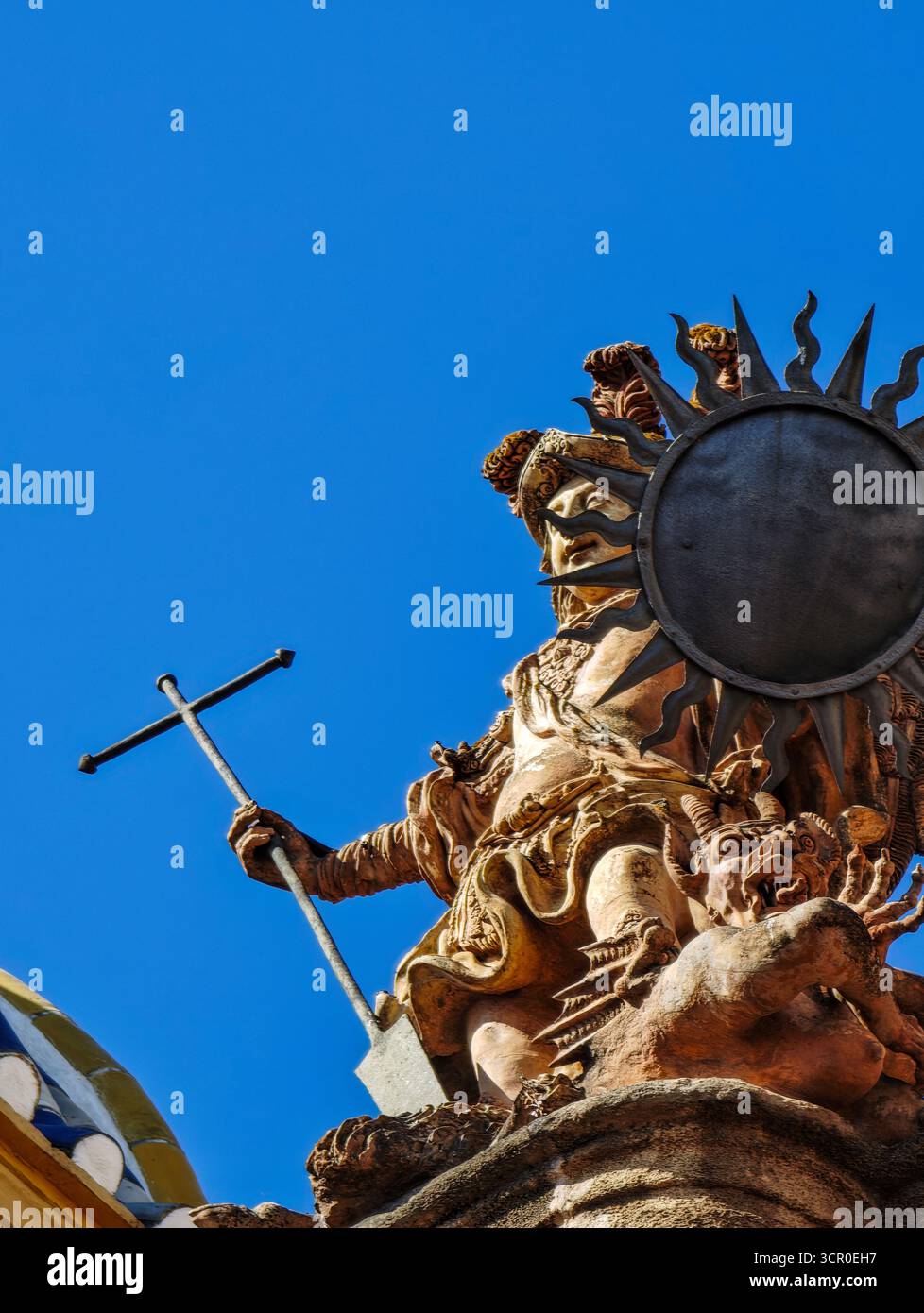 A Siviglia, l'arcangelo Michele si erge orgogliosamente con il suo scudo e il bastone a forma di croce, mostrando una vittoria drammatica sul demone sottostante. Foto Stock