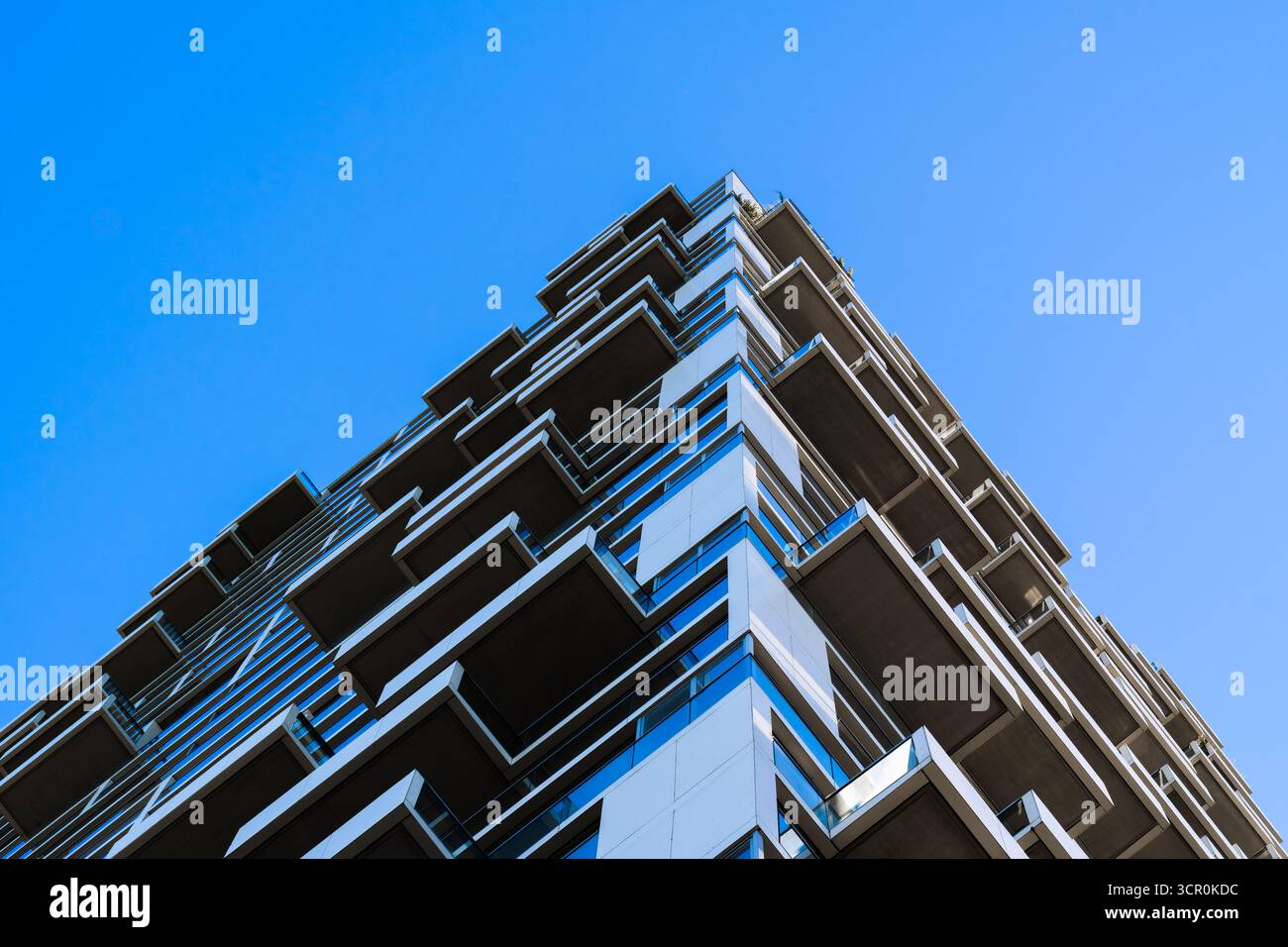 Moderno edificio residenziale con finestre a bovindo geometriche e vetro blu riflettente che creano una struttura architettonica dinamica Foto Stock