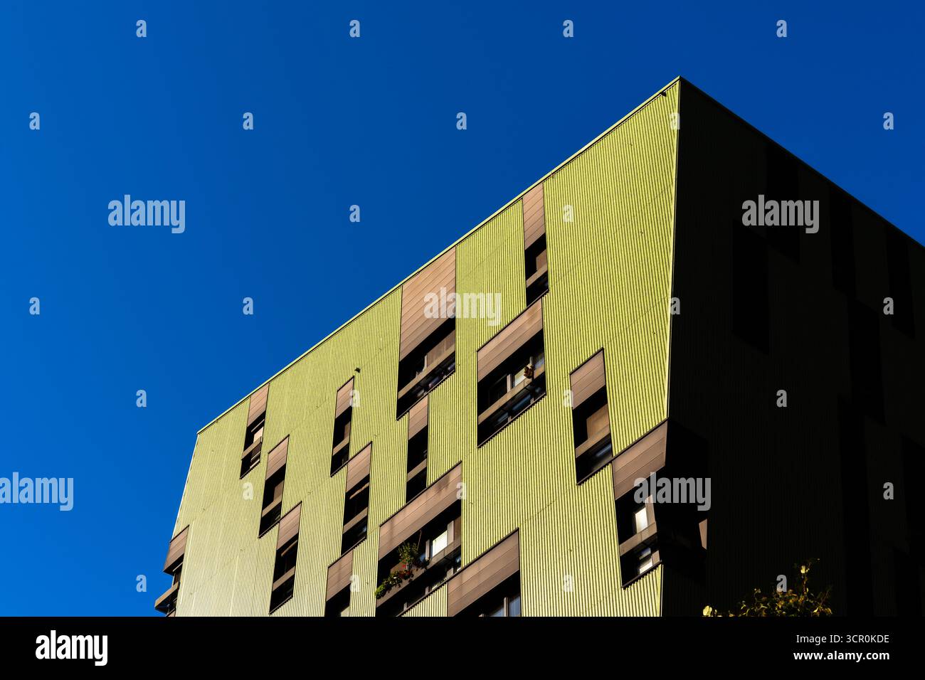 Moderno edificio residenziale con pannelli di facciata verdi e finestre geometriche sotto il cielo azzurro Foto Stock