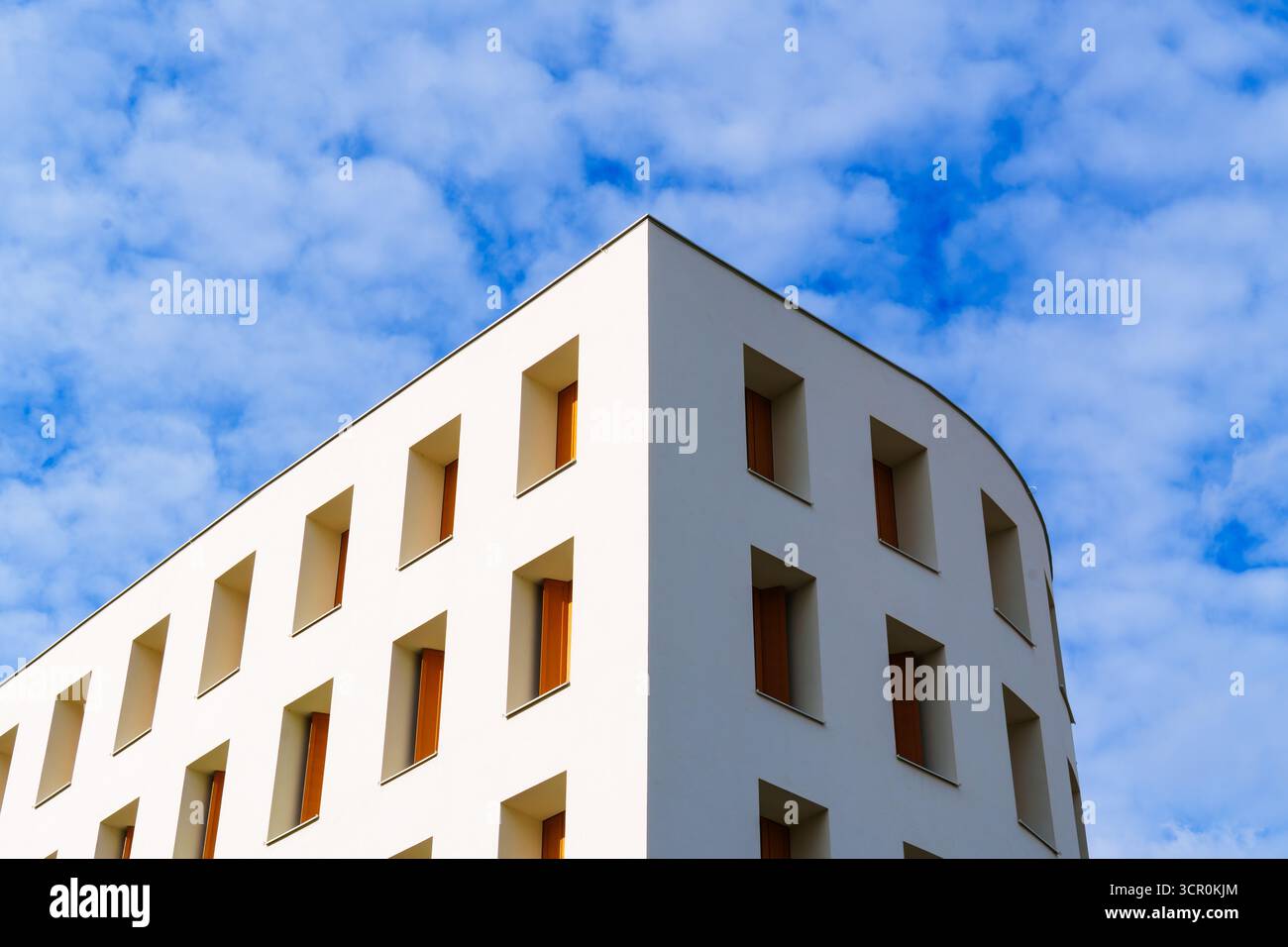 Edificio residenziale minimalista con facciata bianca liscia e finestre incassate sotto un cielo dai motivi blu luminosi Foto Stock