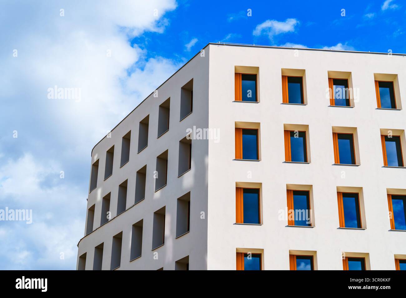Edificio residenziale minimalista con facciata bianca liscia e finestre incassate sotto un cielo dai motivi blu luminosi Foto Stock
