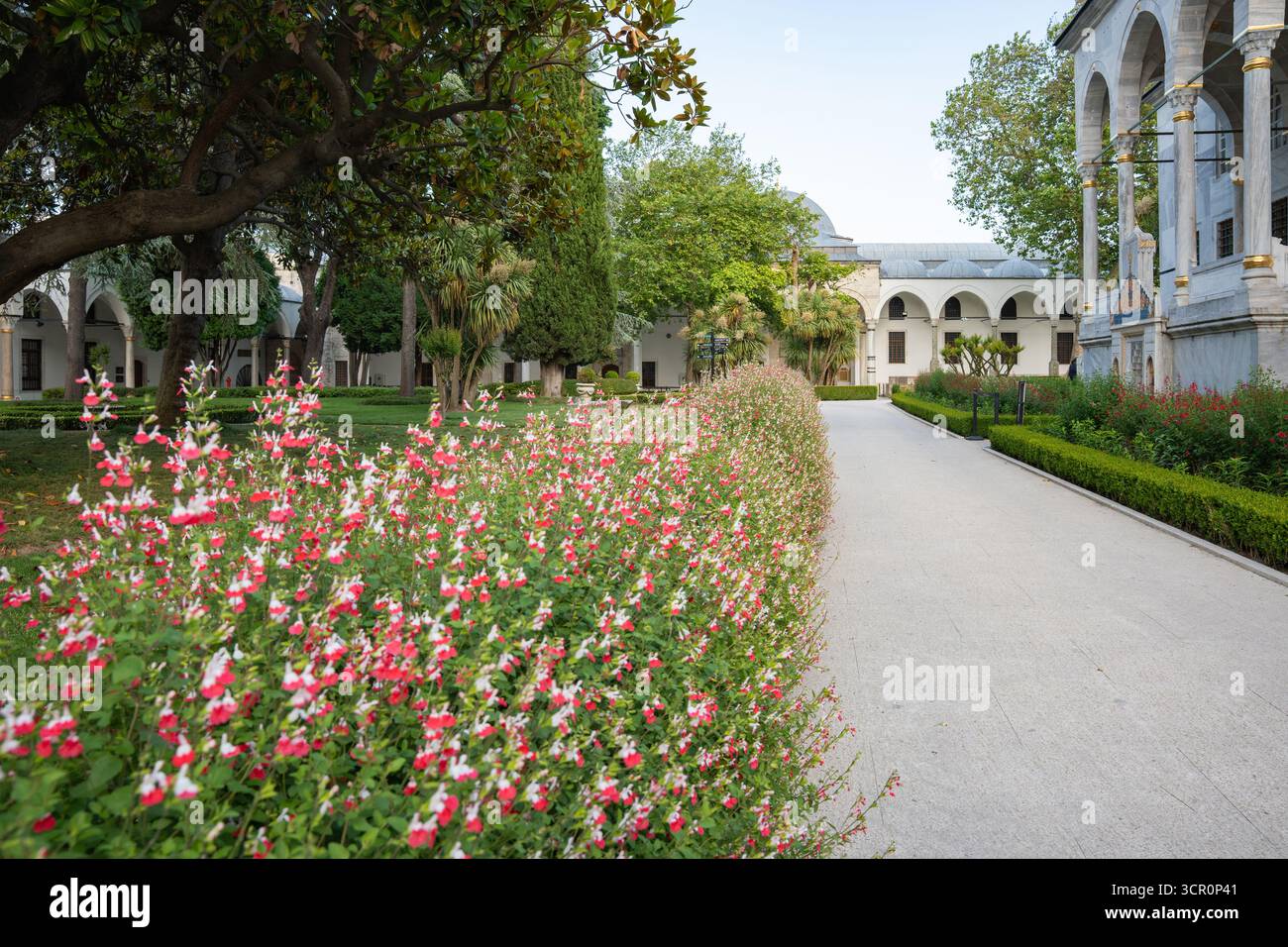 Tranquillo sentiero fiancheggiato da vivaci fiori rossi e bianchi che conduce agli storici portici del Palazzo Topkapi di Istanbul Foto Stock