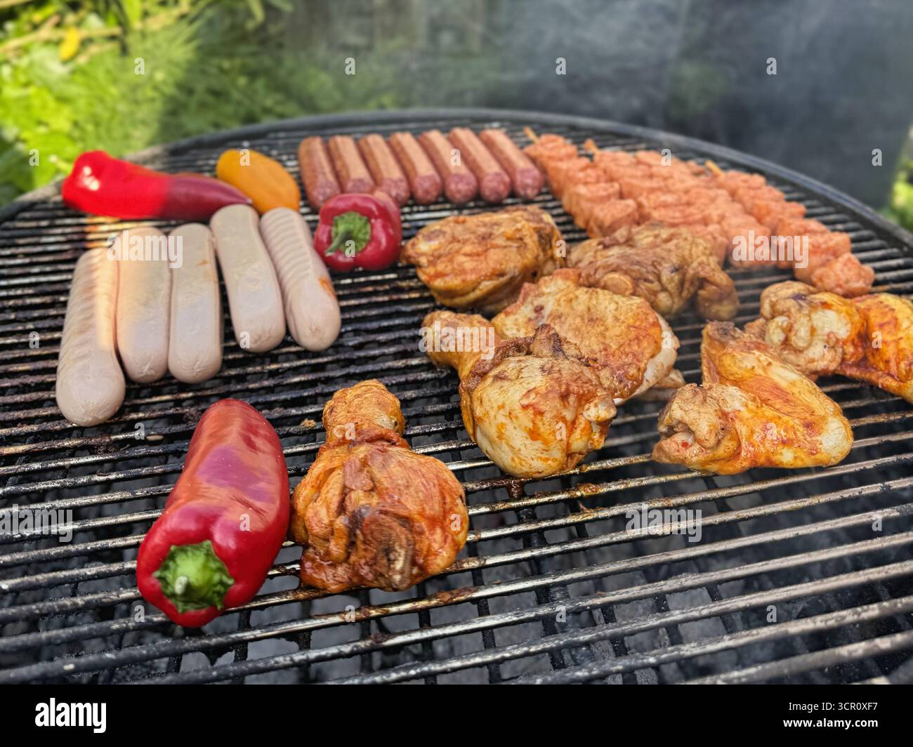 Grigliate con carne di pollo, salsicce e verdure cucinate all'aperto con fumo Foto Stock
