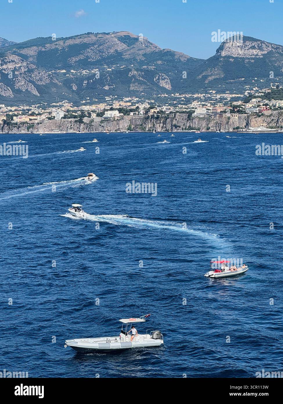 Motoscafi sul mare blu con città costiera e montagne italiane Foto Stock