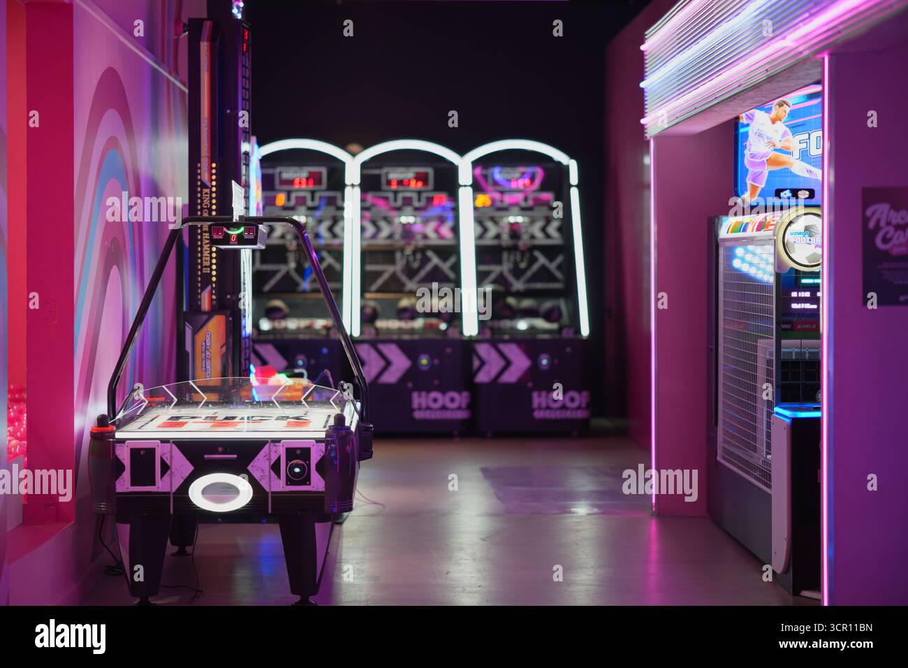 Sala giochi illuminata al neon con hockey da tavolo e altri giochi divertenti in un vivace centro di intrattenimento Foto Stock