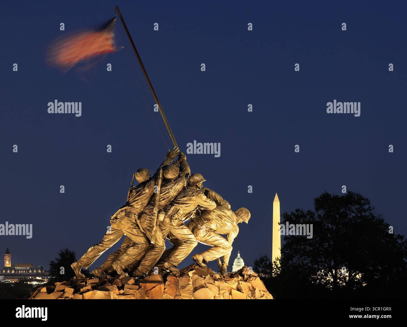 US Marine Corps War Memorial (Iwo Jima) illuminato al crepuscolo con il Campidoglio degli Stati Uniti, il monumento a Washington e la torre postale sullo sfondo Foto Stock