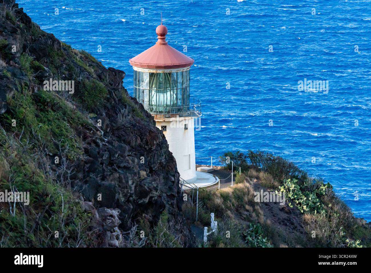 Una vista mozzafiato del faro di Makapu'u sulla costa orientale di Oahu, dove la ricca storia marittima delle Hawaii incontra le incontaminate scogliere oceaniche e l'oceano blu profondo Foto Stock