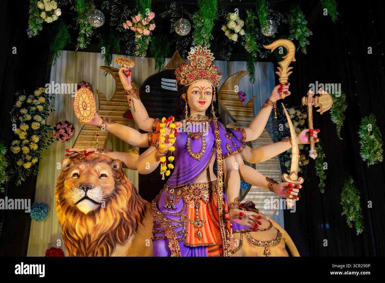 Statua colorata della dea Durga con più braccia in mano armi, seduta su un leone Foto Stock