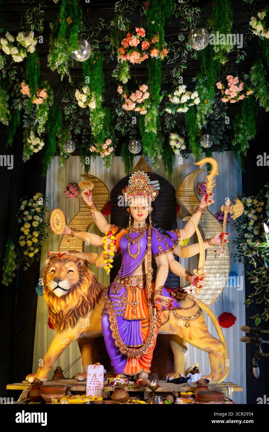 Statua colorata della dea Durga con più braccia in mano armi, seduta su un leone Foto Stock