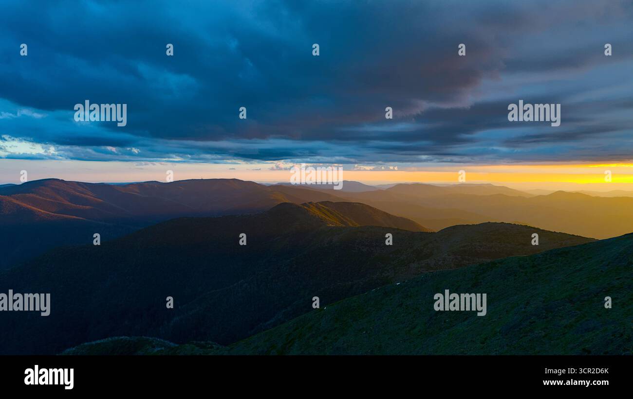 Aspetta che il sole tramonti dalla cima del monte nelle catene alpine vittoriane. Foto Stock