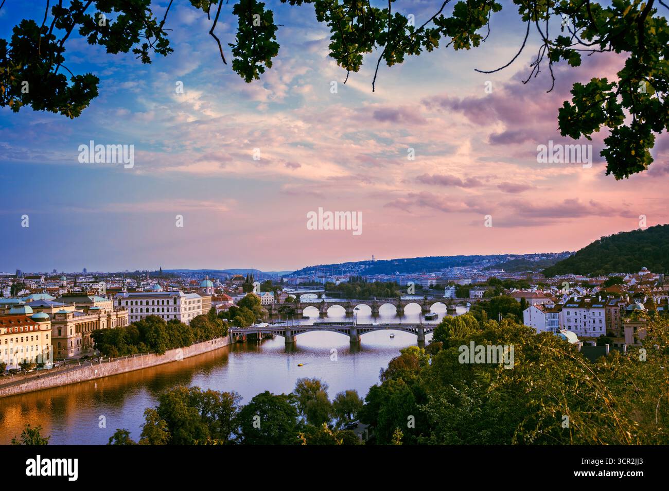 Vista panoramica di Praga al tramonto con ponti storici e riflessi sul fiume. Ideale per viaggi, editoriali e temi lifestyle che mettono in risalto Europa Foto Stock