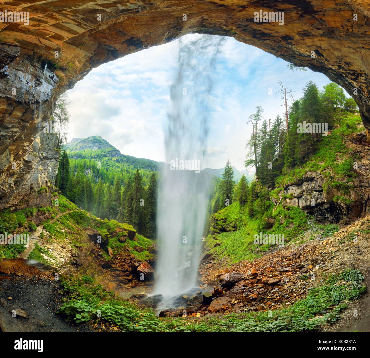 Vista attraverso una cascata in una valle con foreste e montagne: La cascata di johannes, la montagna delle Alpi austriache Foto Stock