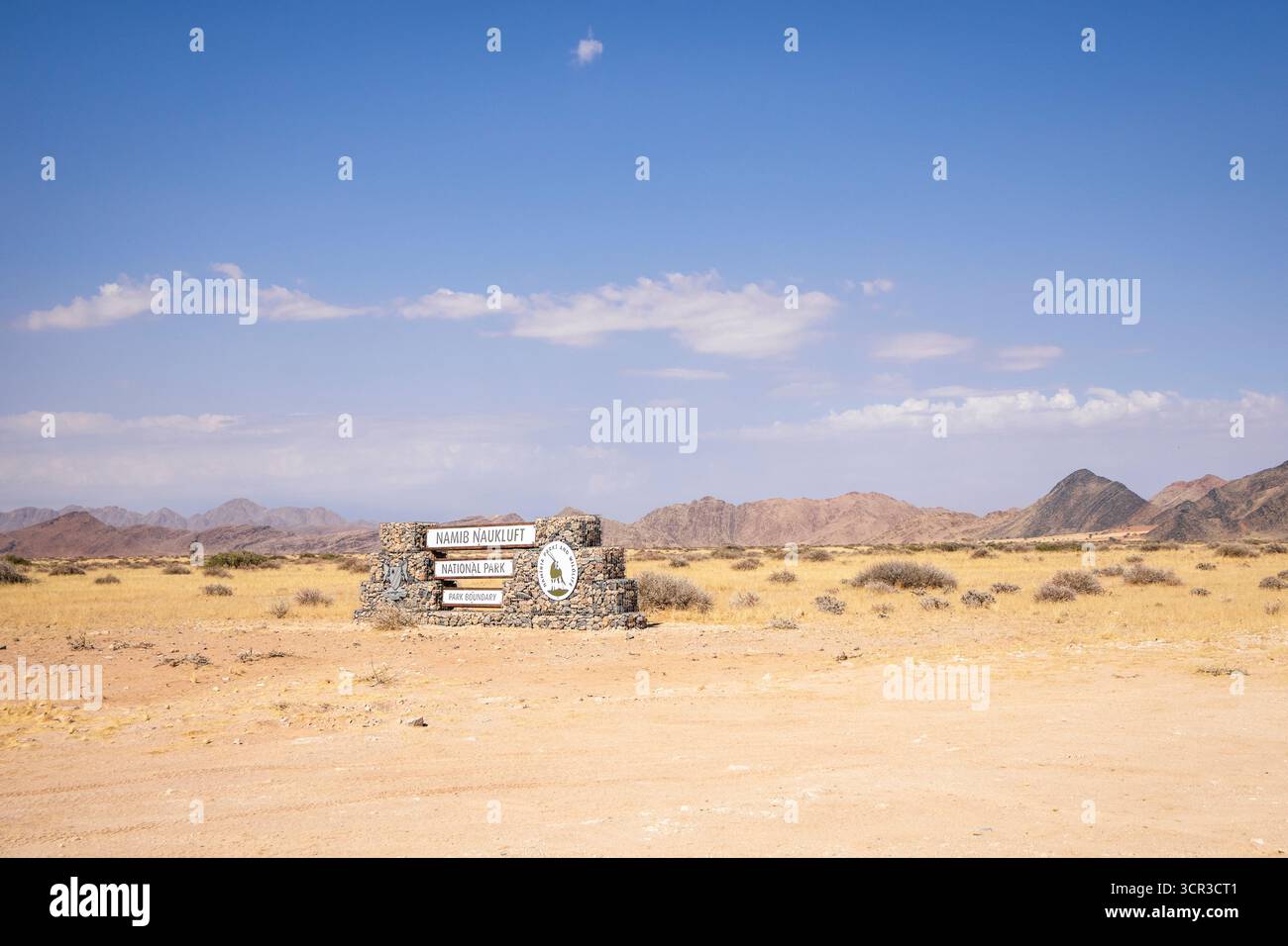 Cartello di ingresso in pietra del Parco Nazionale Namib-Naukluft in Namibia - 27 agosto 2025: Circondato da pianure desertiche e catene montuose lontane. Foto Stock