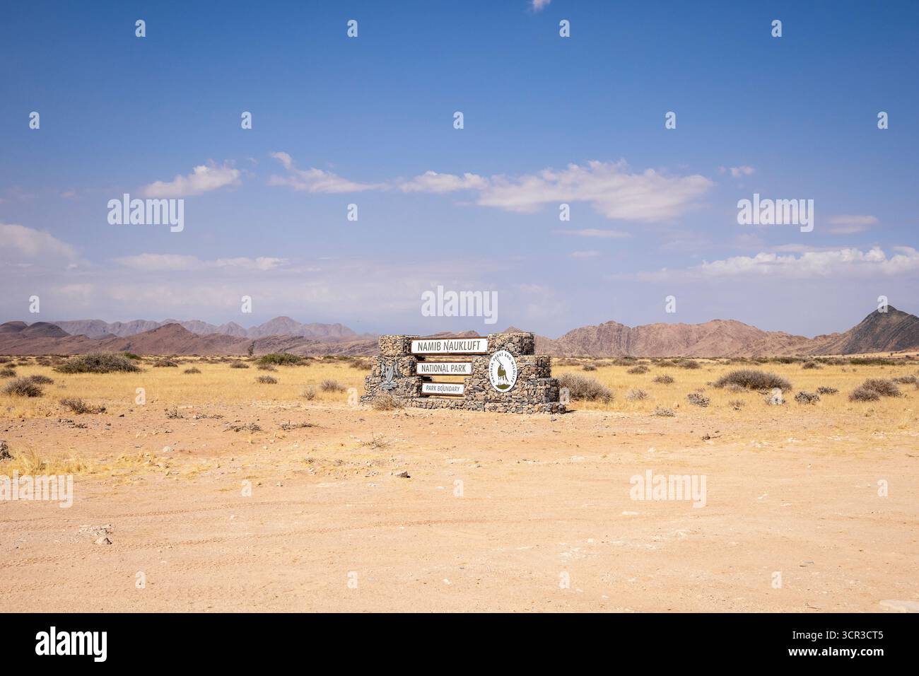 Cartello di ingresso in pietra del Parco Nazionale Namib-Naukluft in Namibia - 27 agosto 2025: Circondato da pianure desertiche e catene montuose lontane. Foto Stock